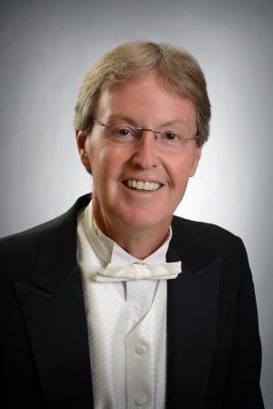 Stephen Gage A headshot of a smiling businessman wearing a suit and bowtie and glasses