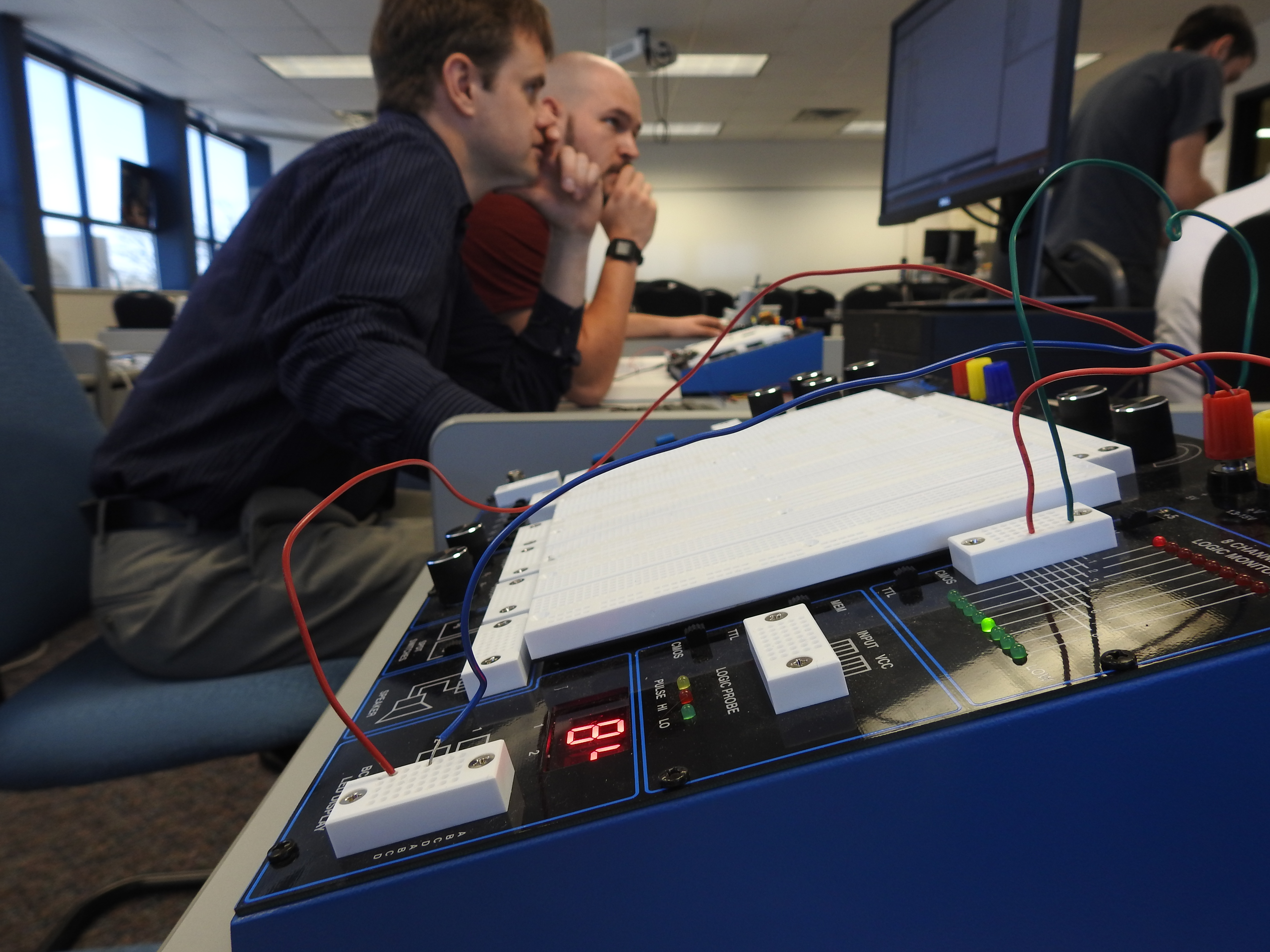 Professor and student working in the background of a photo of the Global Specialities PB-505 Deluxe Analog and Digital Design Workstation