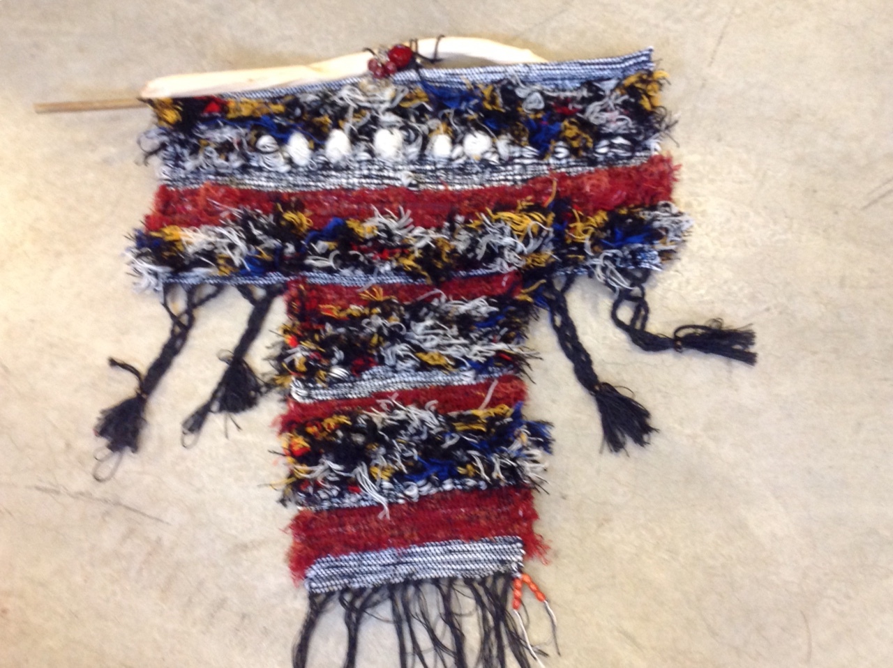 A handwoven rug with red, blue, black and white fibers woven into it