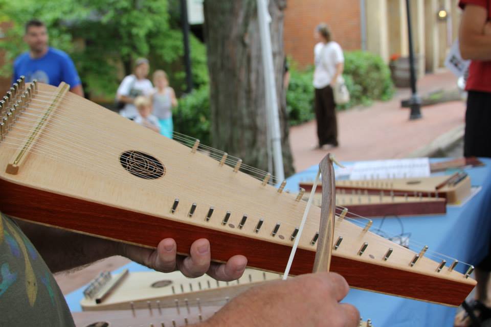 A string instrument made of wood and a man playing the instrument 