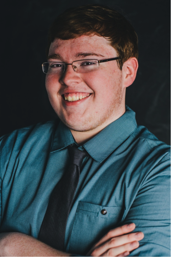 A posed senior photo style photo a student smiling and wearing a blue button up shirt