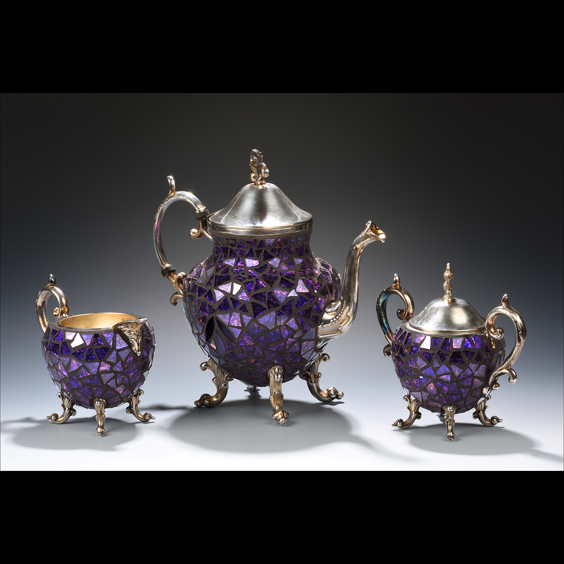 Two purple teapots with a purple teacup