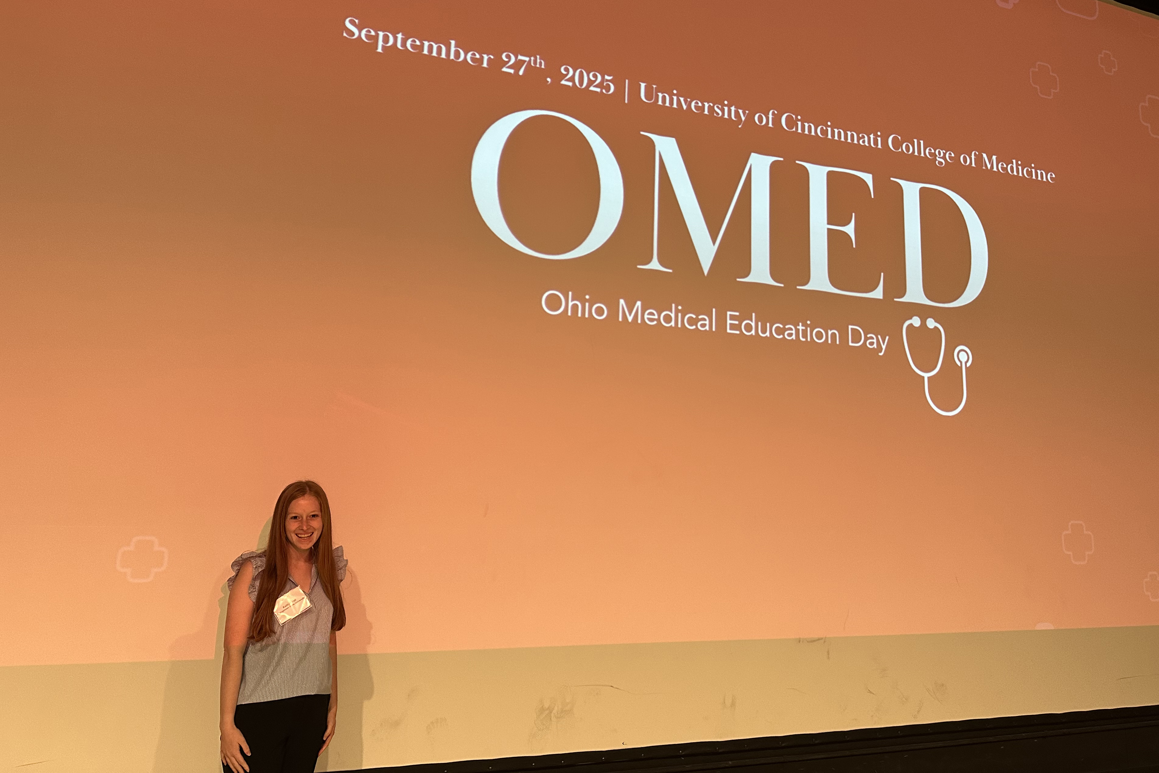 Kaitlyn Vail in front of the OMED Ohio Medical Day logo she designed