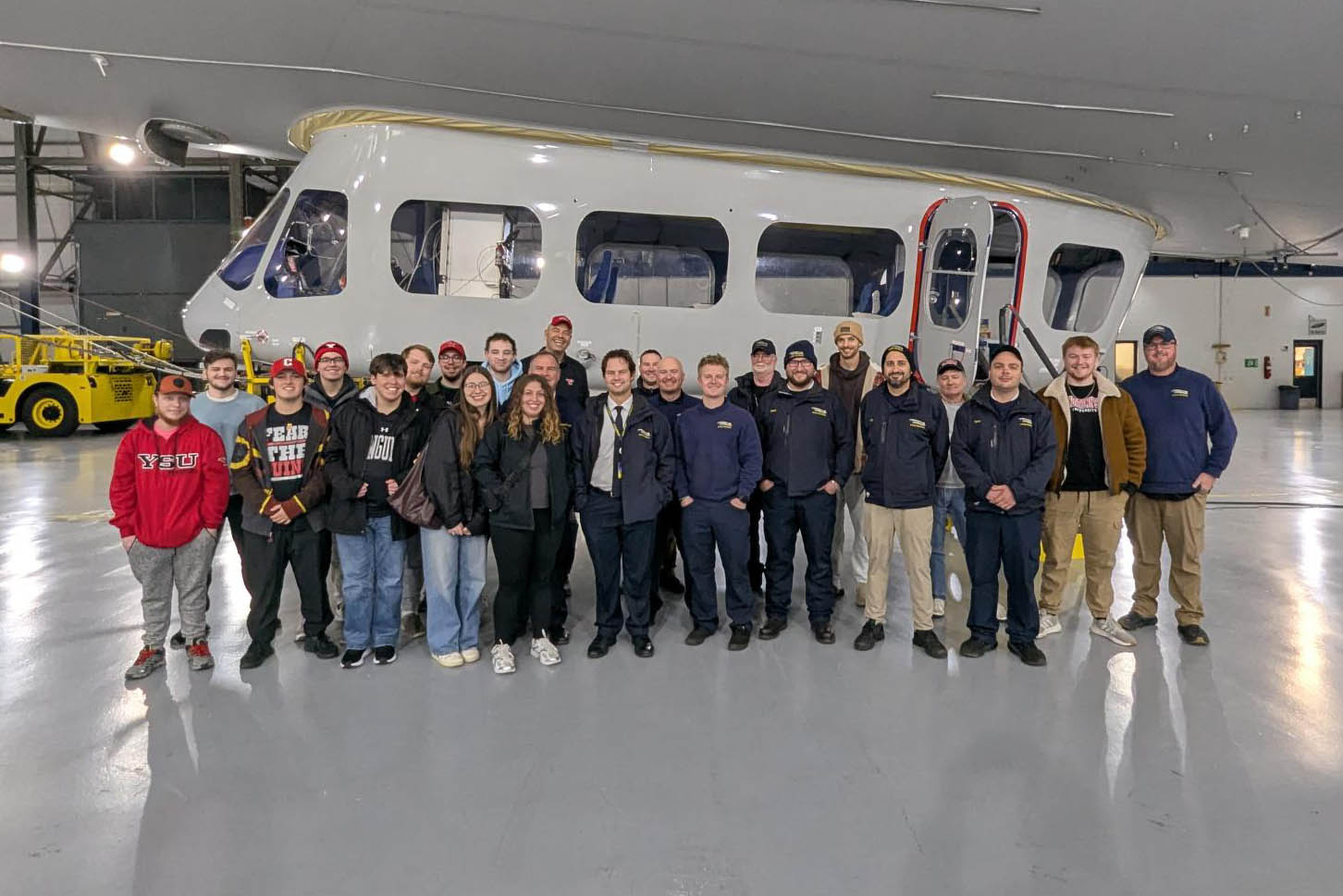 Group photo of students in the hangar with the Goodyear Blimp