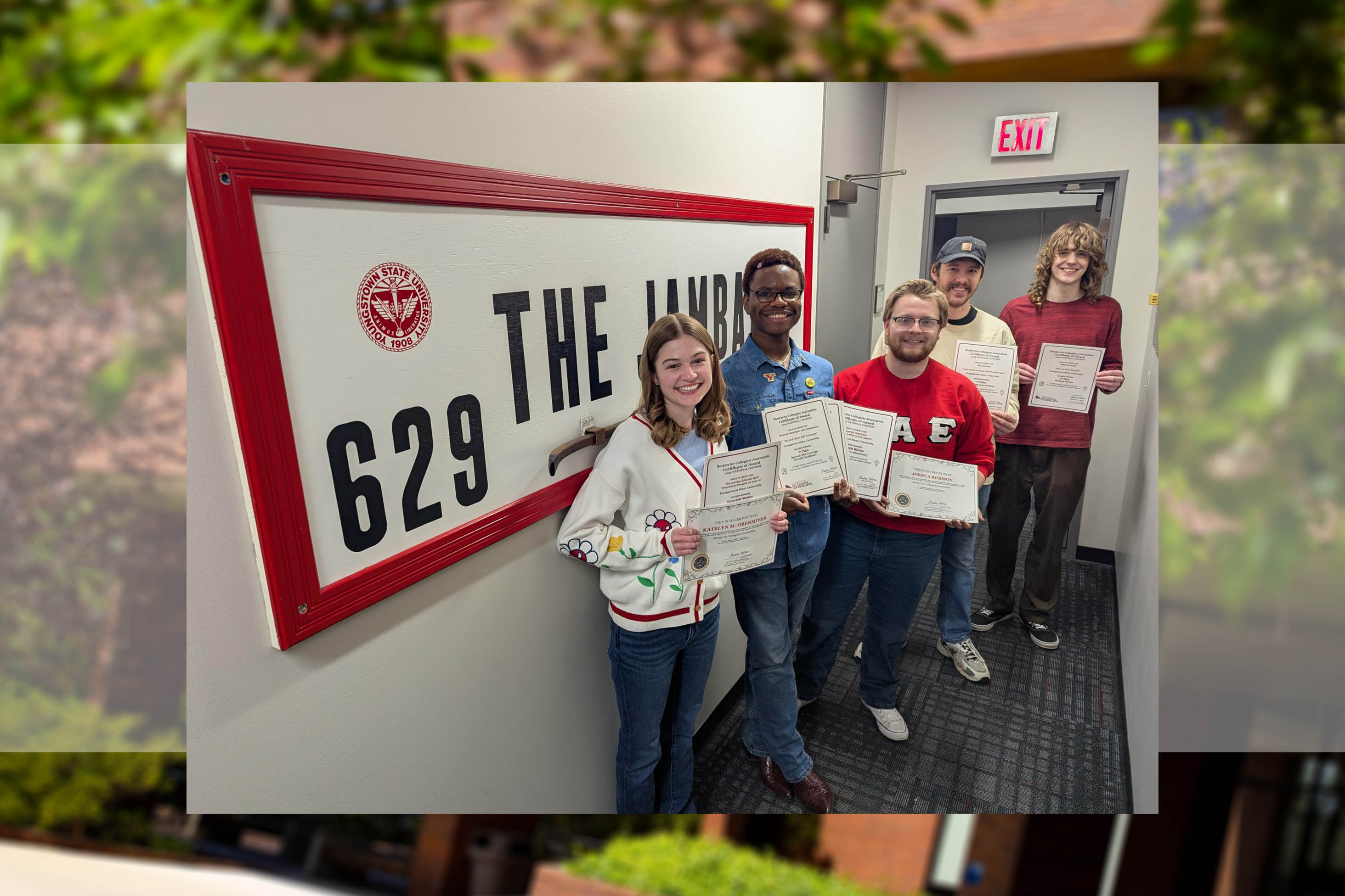 Students pose with their SCJ certificates in front of the Jambar logo