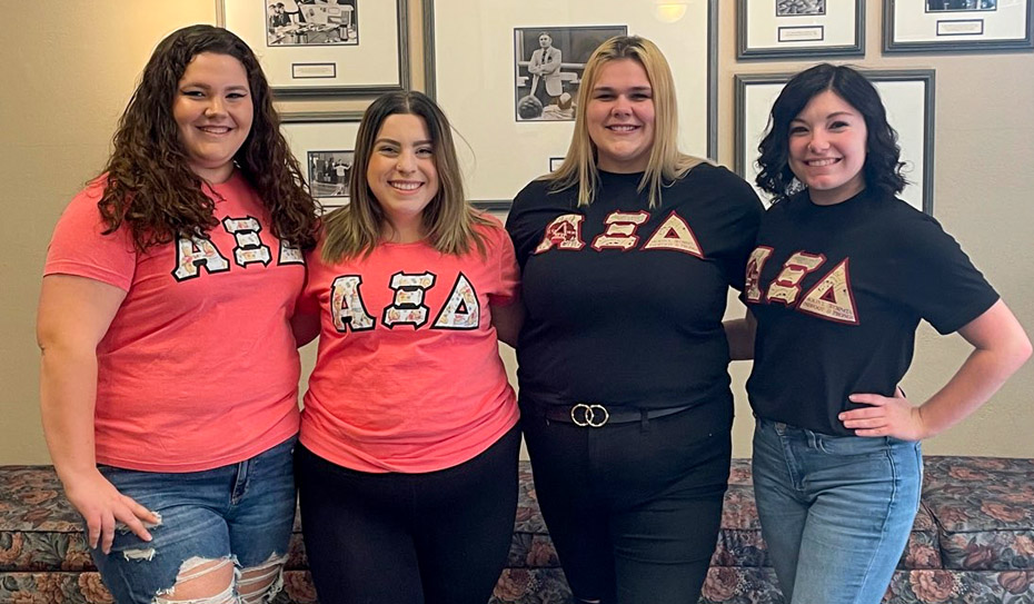 4 girls wearing shirts with Alpha Xi Delta letters