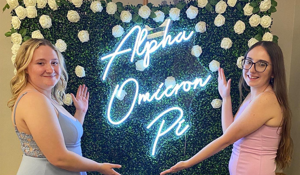 2 Alpha Omicron Pi girls by sign