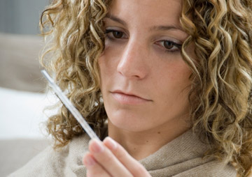 Woman checking for fever with thermometer