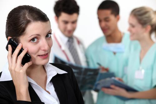 Woman talking on phone.  Three medical professionals in background.