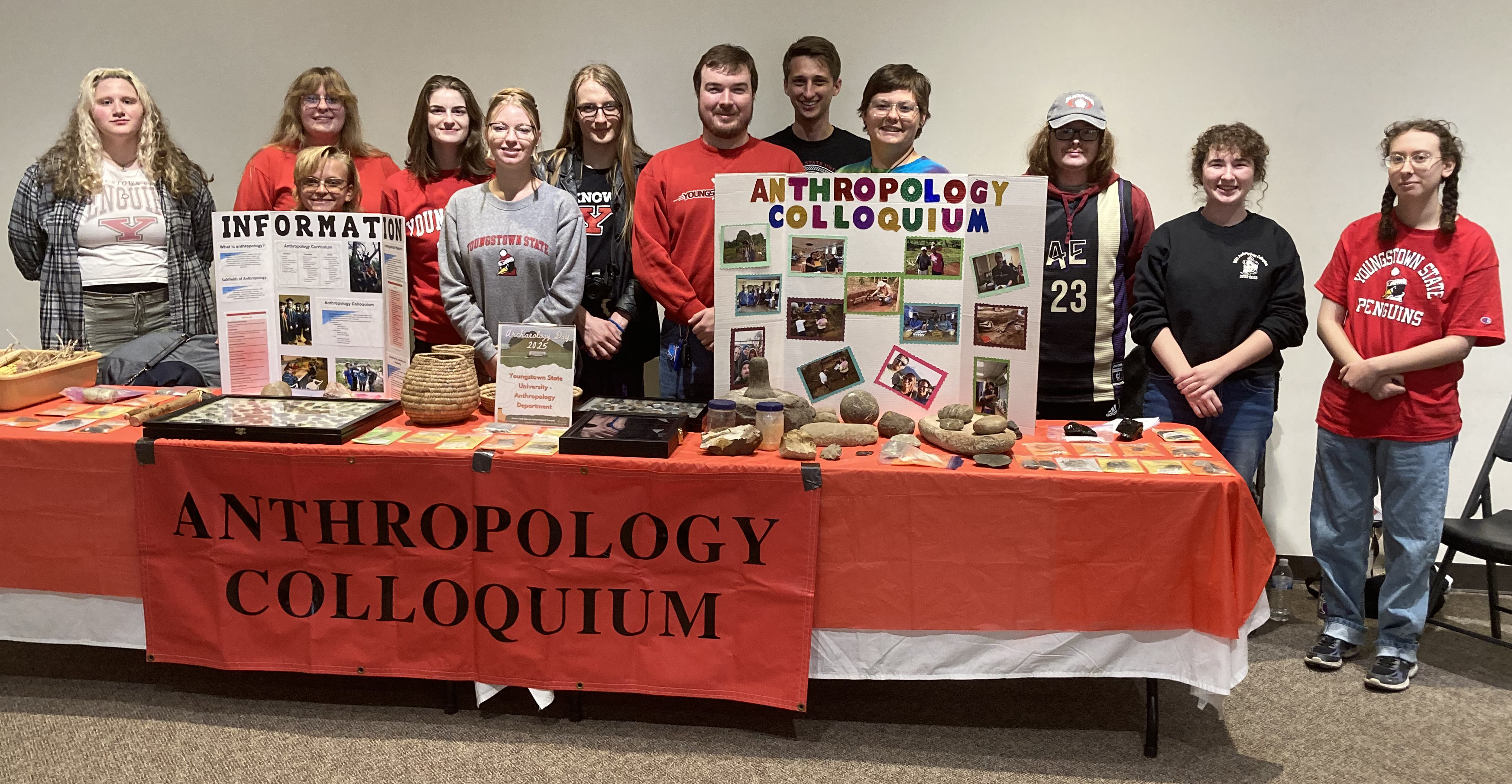 12 students from YSU posing in front of their display for West Virginia Archaeology Day at the Grave Creek Mound Archaeological Complex in Moundsville, West Virgina