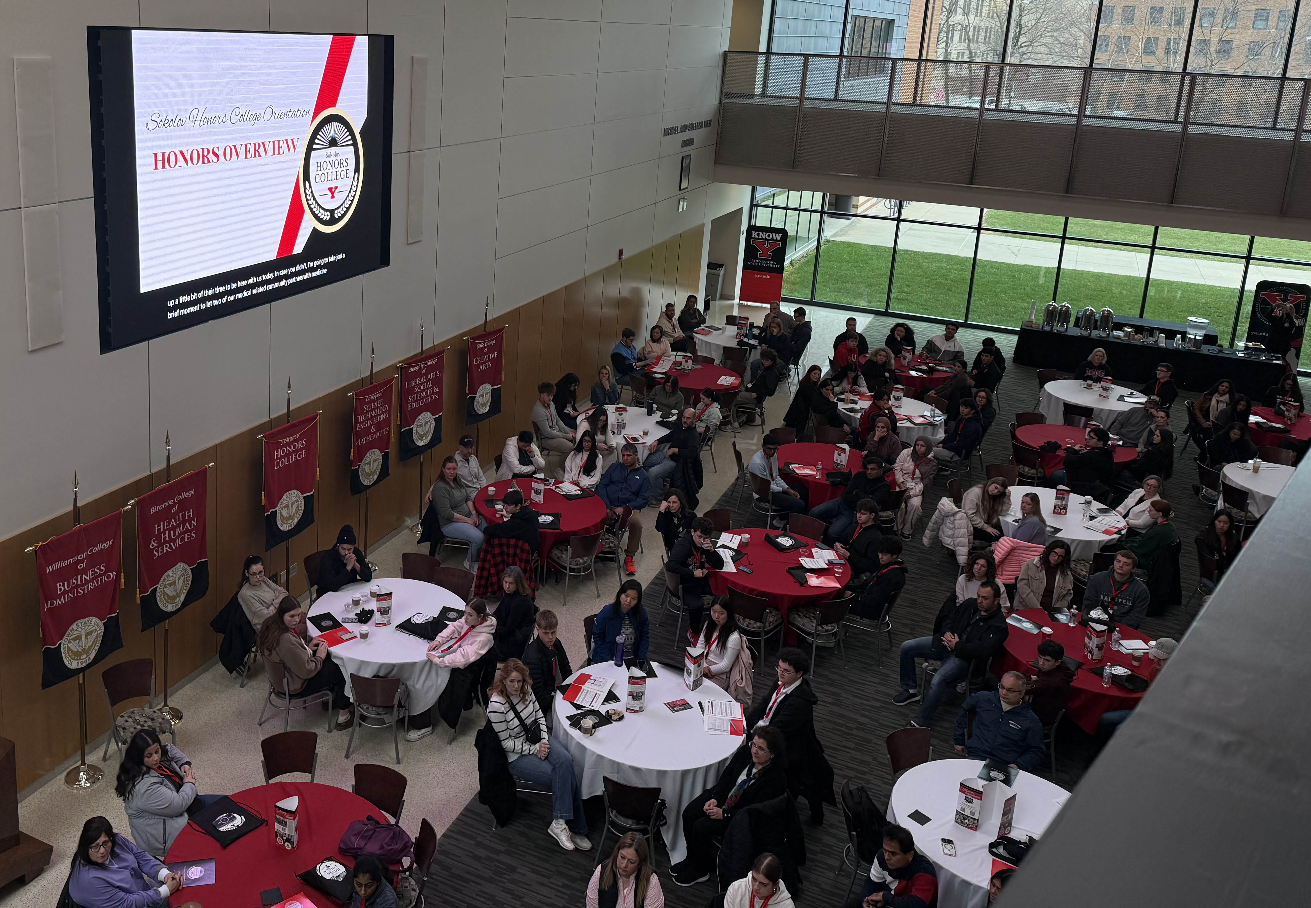 Aerial view of students and parents sitting at tables in the WCBA Atrium for Honors Orientation