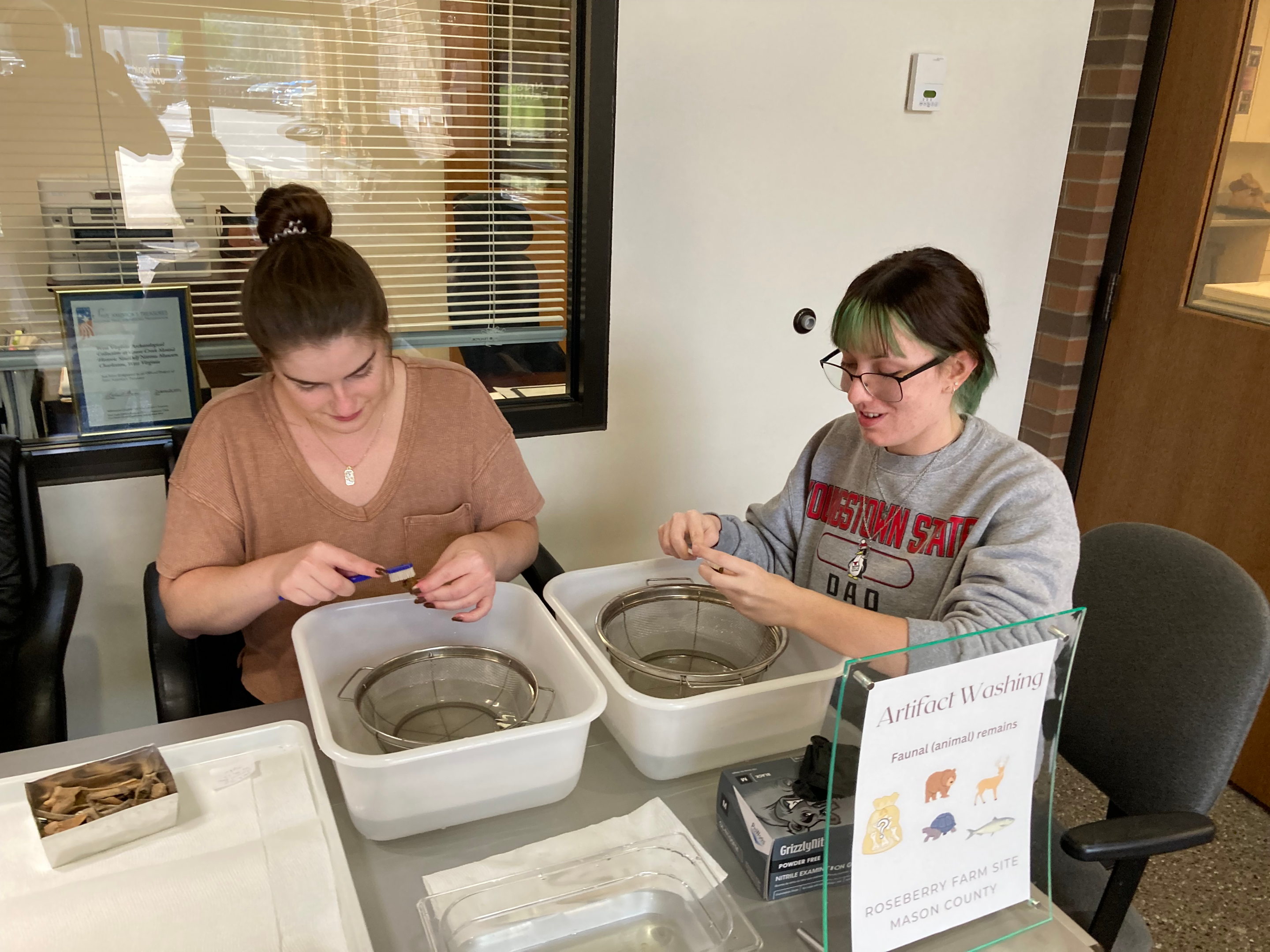 Emily McNett and Alex Hubaker washing artifacts in the repository.