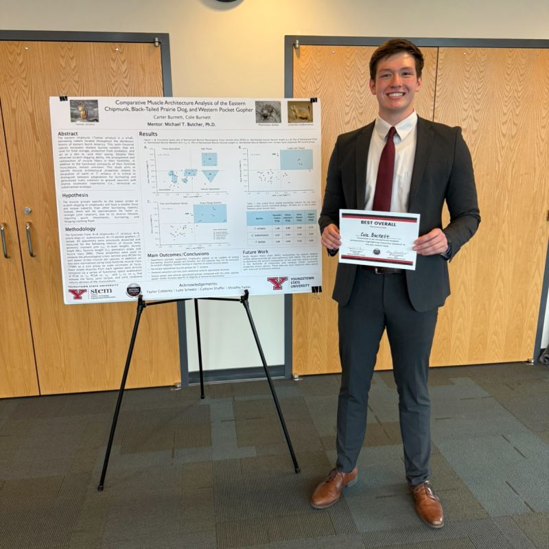Youngstown State University student Cole Burnett stands beside his research poster after receiving the Best Overall Presentation award at the YSU Honors Pre-Health Symposium.