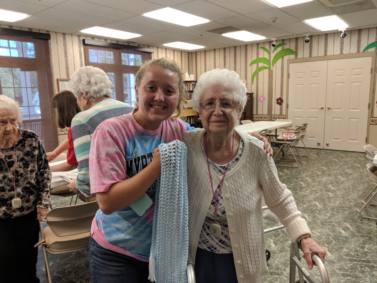 First-year Honors College student Shelby Slomers is pictured with Mary Mariano, a resident at Mercy Health Marian Assisted Living Center in North Lima. Mariano makes scarves in memory of her son who died at age 22. She gave Slomers the scarf as a gift after spending the morning making greeting cards together and sharing in conversation.