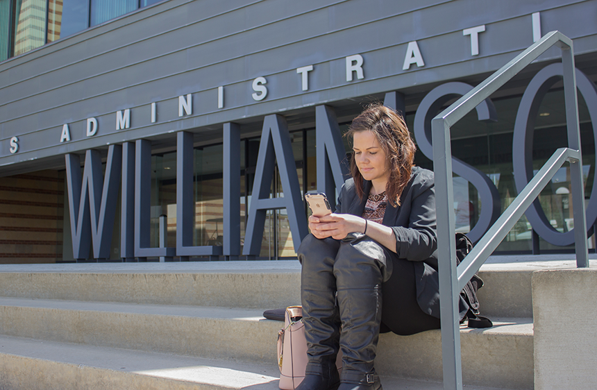 student using smartphone in front of wcba building