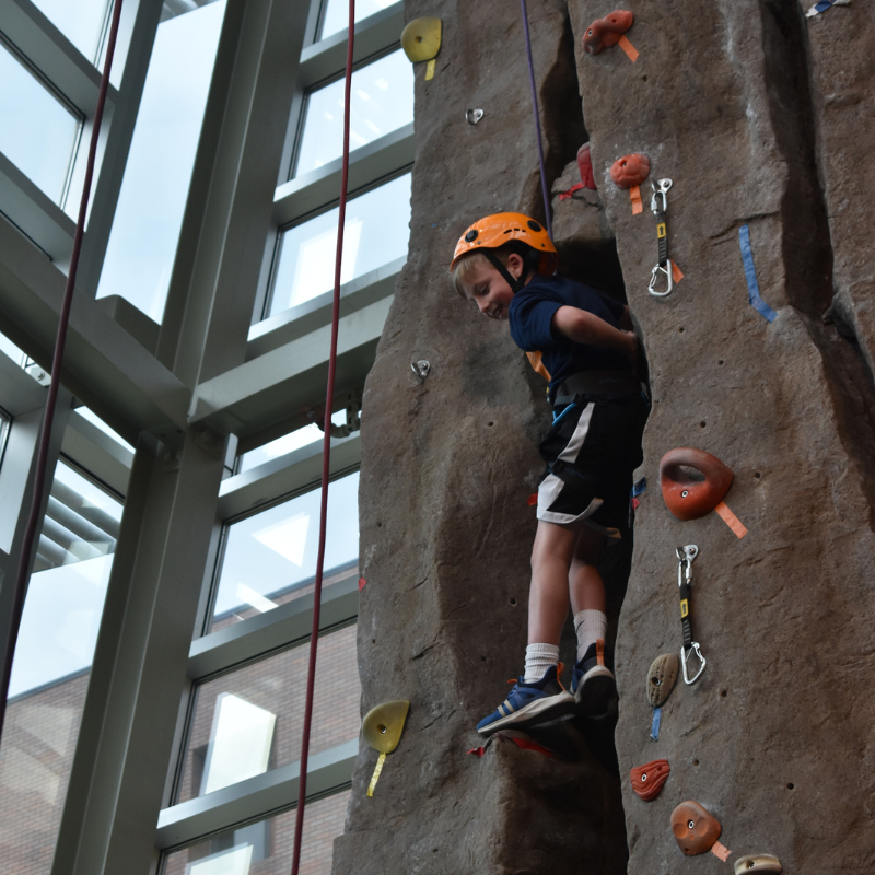 Summer camper climbing the rock wall in the Rec Center.
