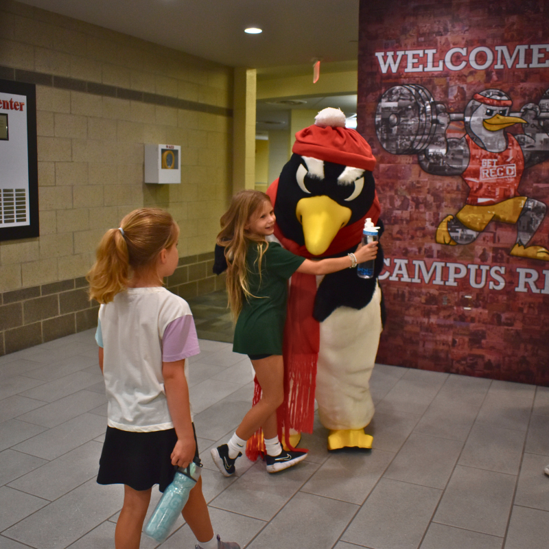 Summer camper hugging Pete the Penguin in Rec Center lobby.