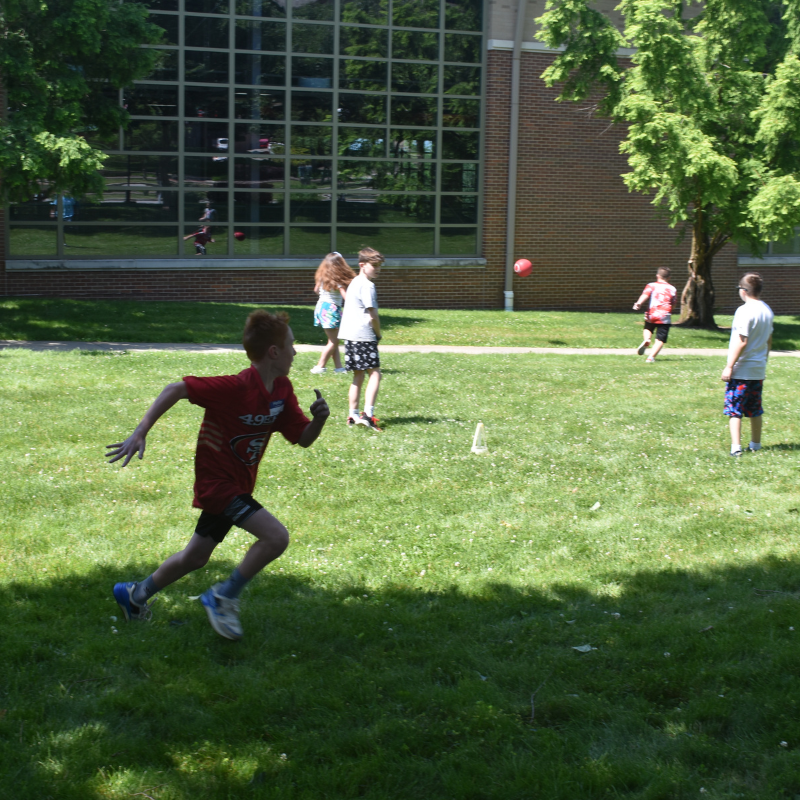 Group of children playing kickball on Campus Rec lawn.