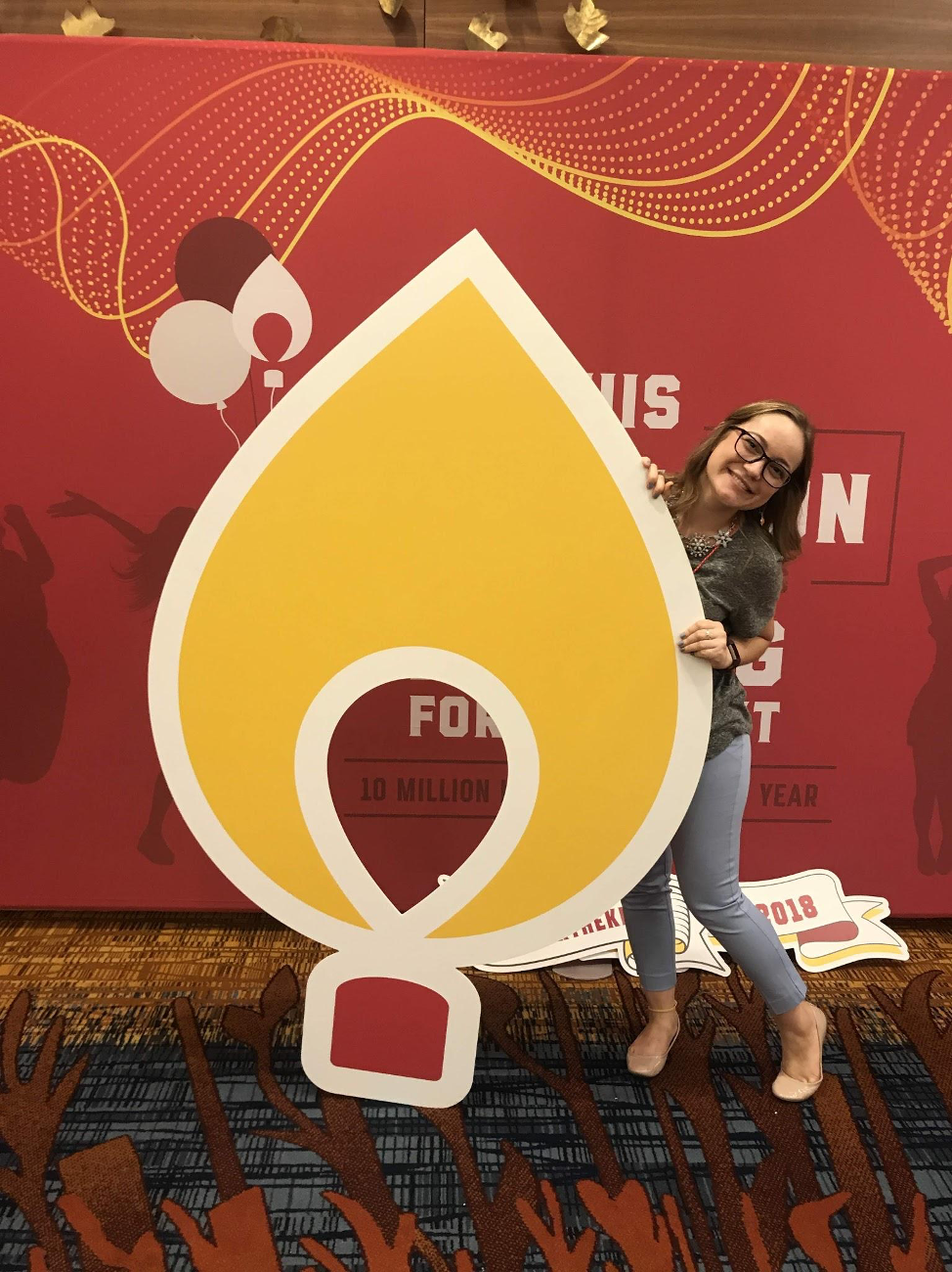 A student poses with a Dance Marathon logo cardboard cutout