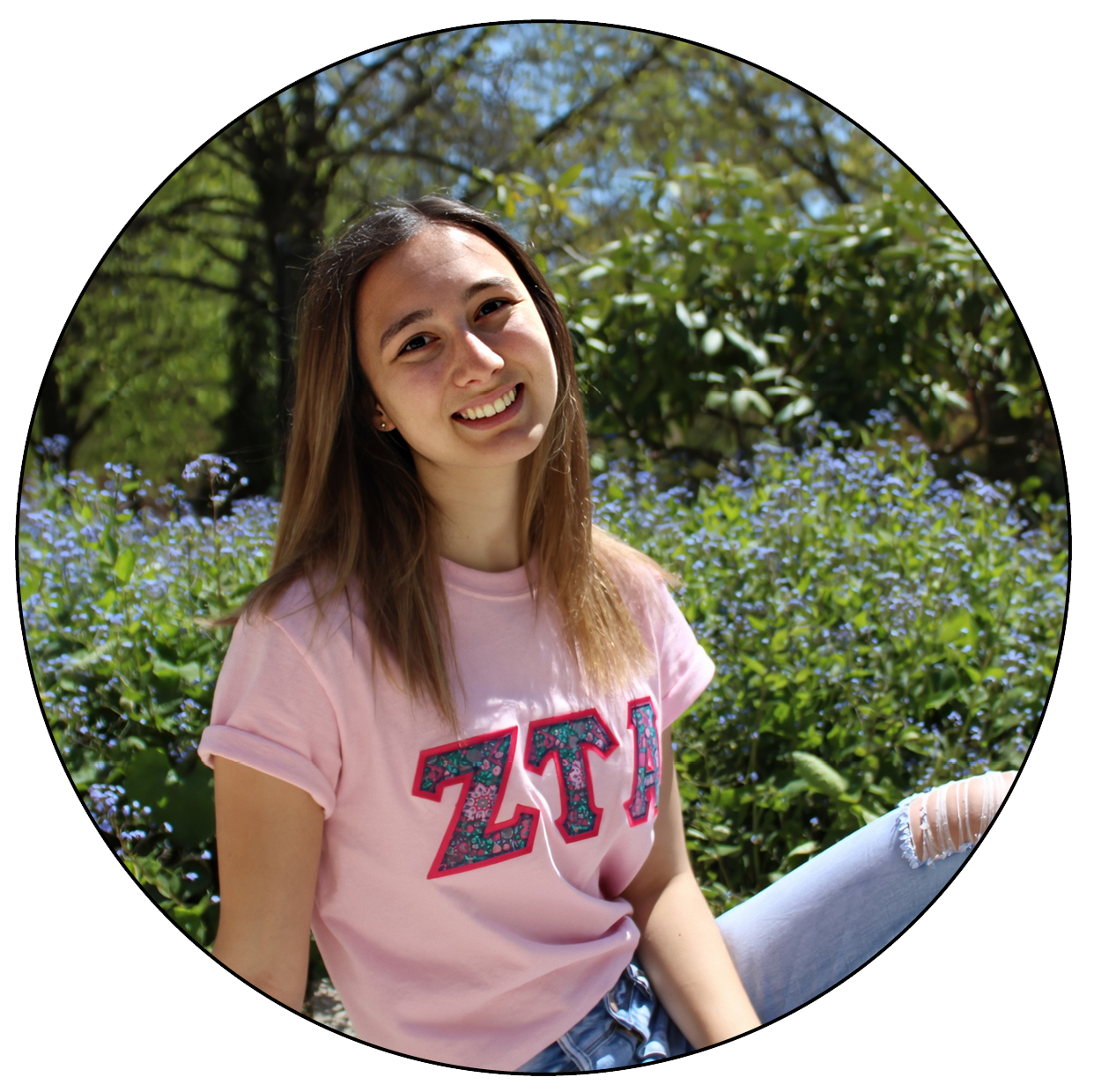 Student wearing a pink shirt with the letters Z-T-A on the front, posing outside