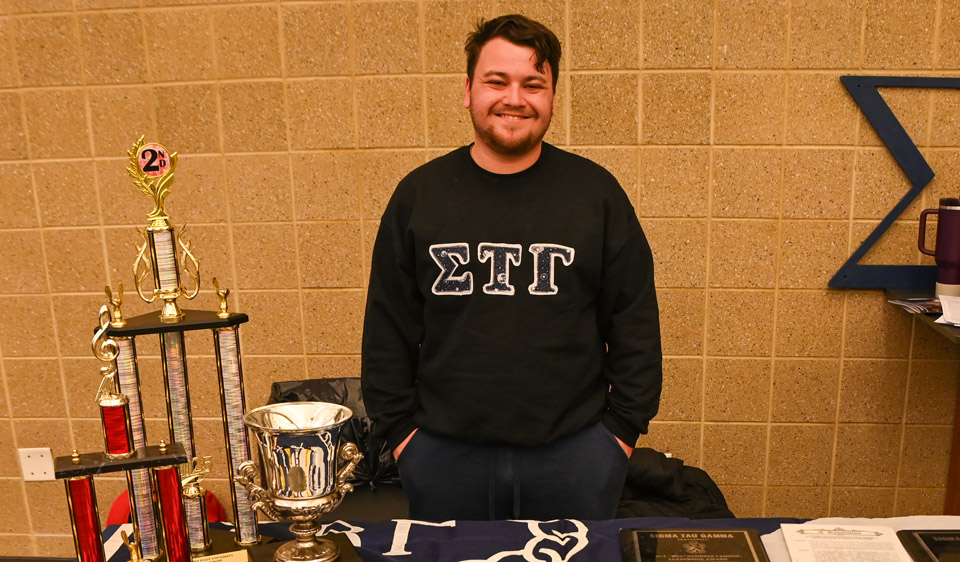 Sigma Tau Gamma member with trophies