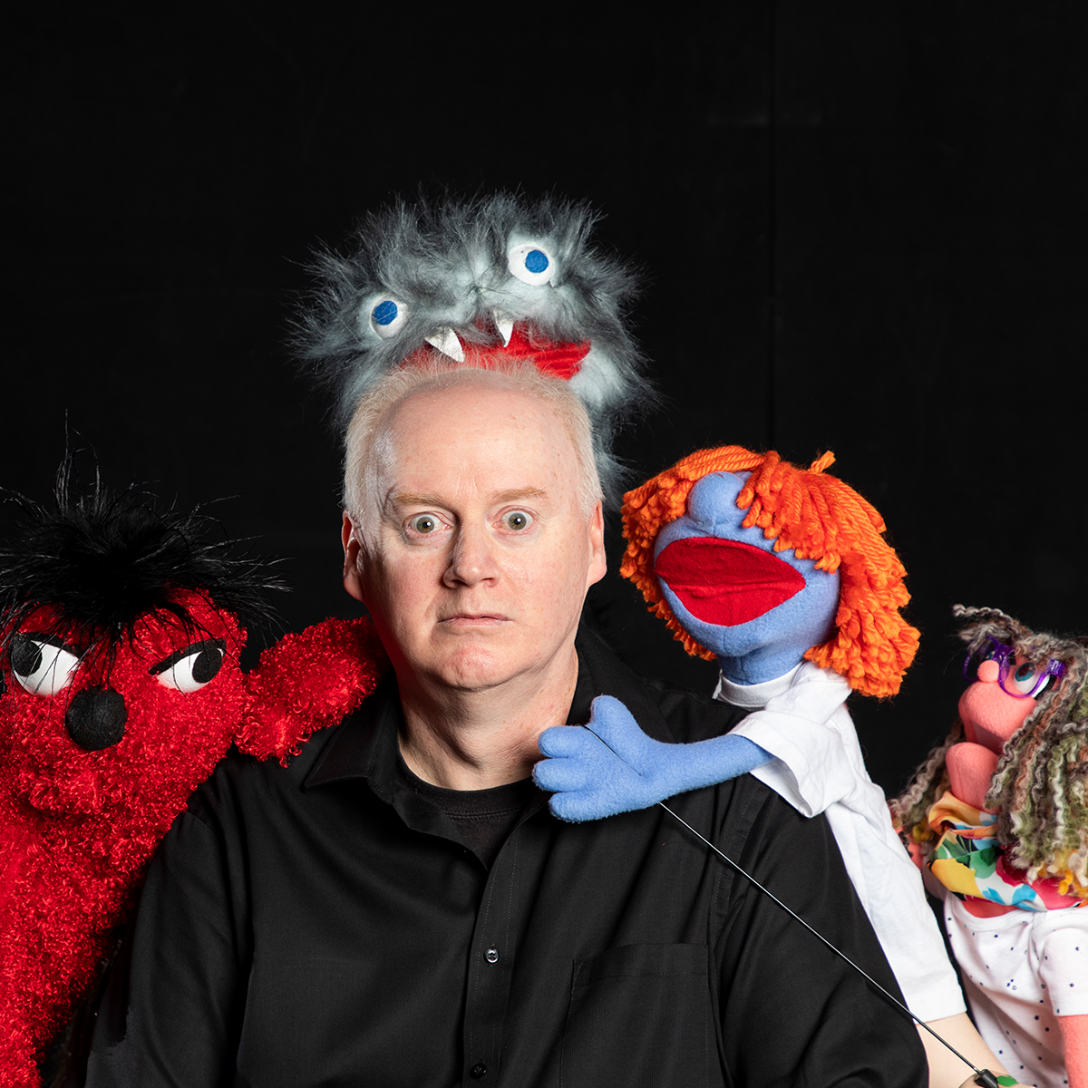 Professor Todd Dicken poses with four puppets
