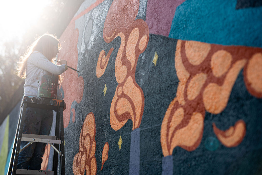 Lindsay DeLullo painting a mural on Andrews Avenue