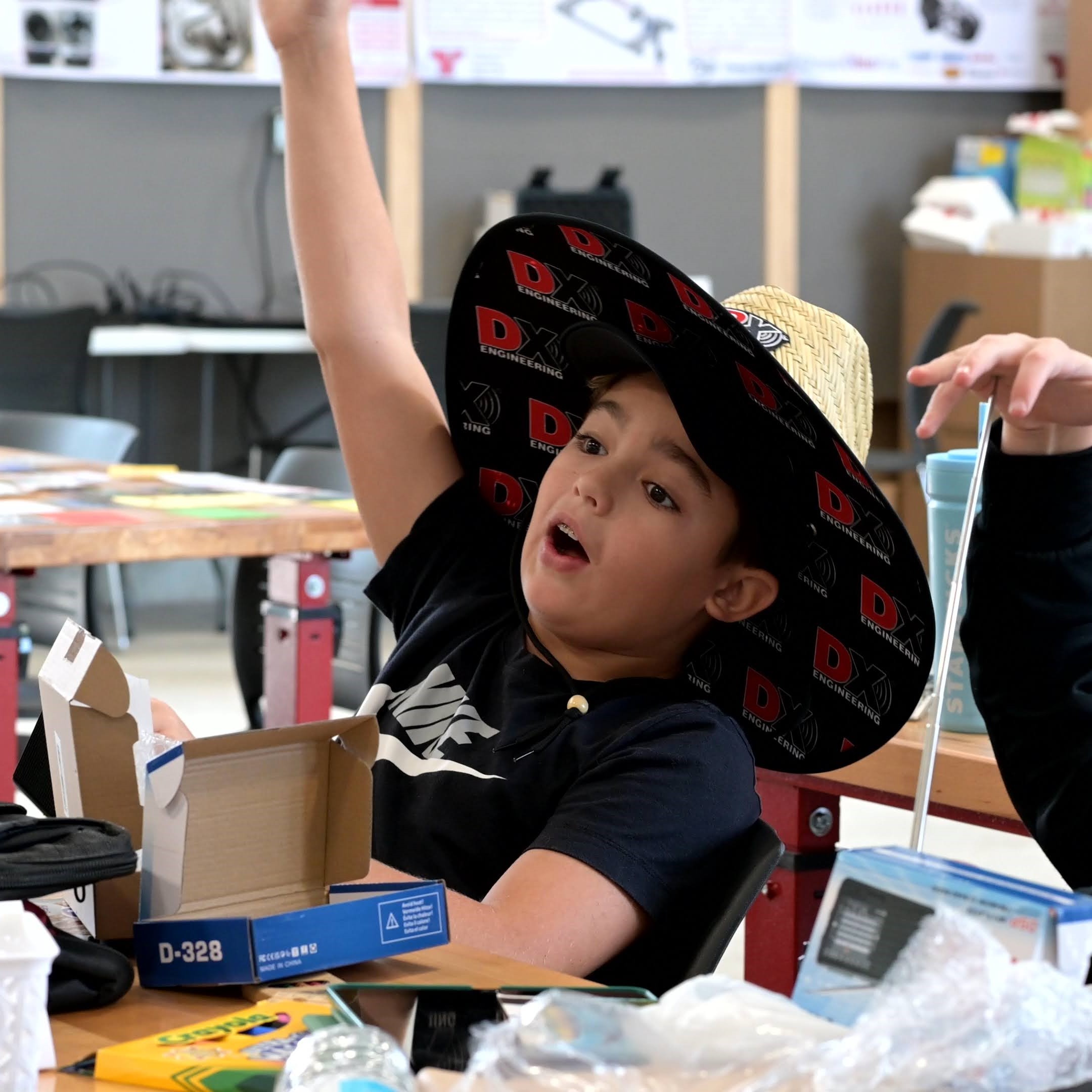 Boy wearing a sombrero excitedly raises his hand