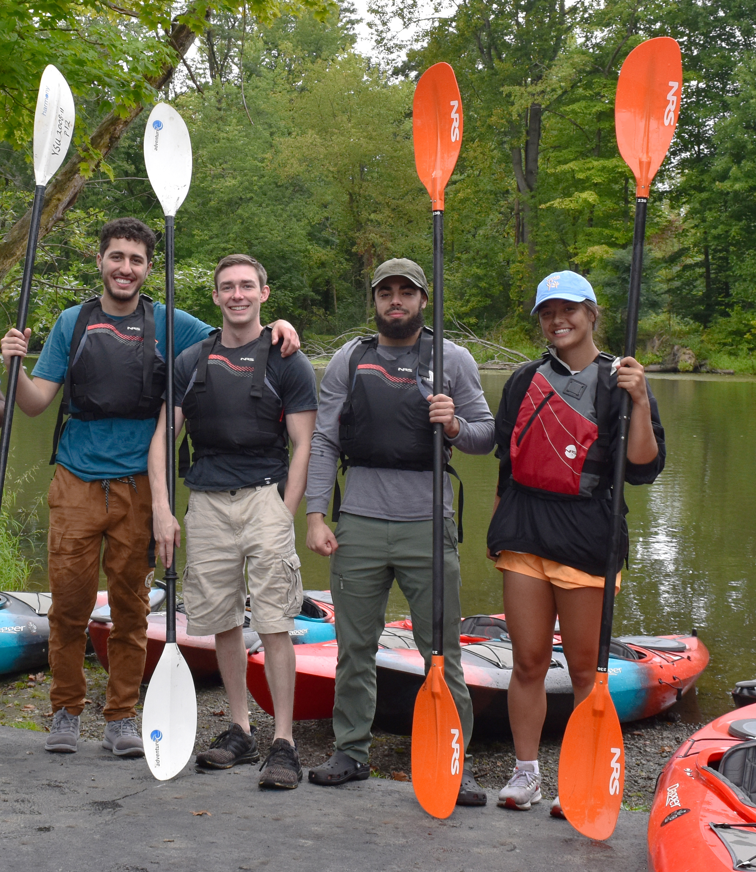 kayakers smiling standing in front of river