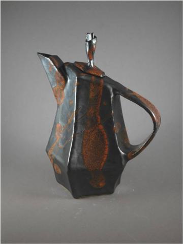 A teapot made out of clay that has an orange design down the sides to give it a rust appeal