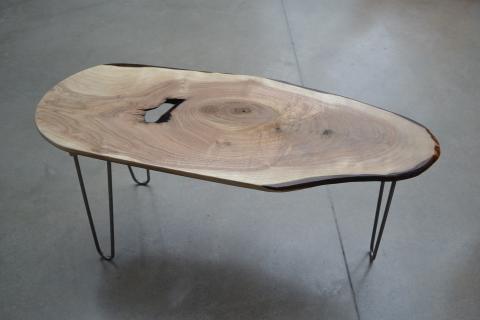 A table with a wood surface and black legs designed by Clayton Fant