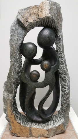 A sculpture of a four person family holding hands inside a stone circle