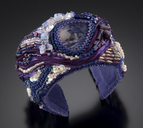 A ring made out of purple and white beads