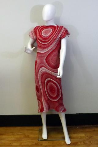 A full size mannequin wearing a woven red and white swirl dress that is cut at tea length and has short sleeves