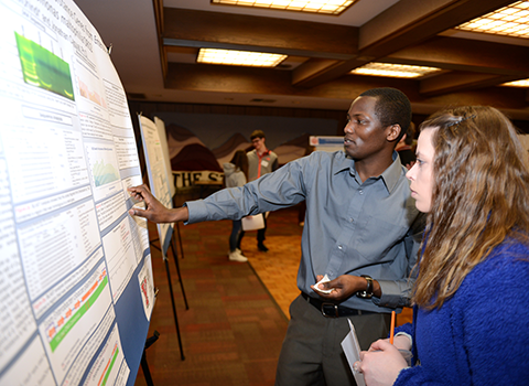 A student explaining his poster to a person