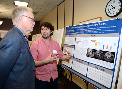 A student explaining his poster to a person