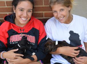 Two students holding puppies